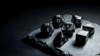 Black polyhedral dice set on dark slate surface for tabletop gaming and role-playing adventures with dramatic lighting and shadows.