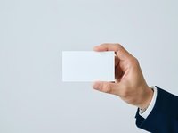Male hand in dark business suit holding blank white card against neutral background for branding and corporate identity mockups.