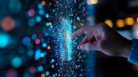 Hand touching glowing digital particles with blue bokeh lights in dark background, representing technology interface and data visualization concept.