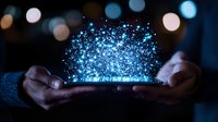 Magical glowing blue particles floating above smartphone in dark environment with bokeh lights, hands holding device showing digital transformation concept.