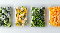 Frozen vegetables in plastic bags arranged in row showing broccoli, mixed corn and squash, peas with broccoli, and diced carrots for healthy meal preparation.