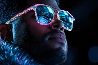Young African American man wearing crystal-embellished sunglasses with blue neon reflections in dark atmosphere. Dramatic portrait with modern cyberpunk aesthetic.