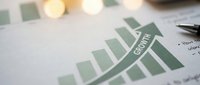 Business growth chart with green bars showing upward trend on financial report with pen and calculator for corporate analysis and planning.