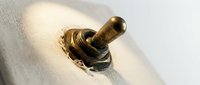 Worn brass toggle switch with patina and rust on white textured surface, showing aged metal hardware for industrial design and restoration projects.