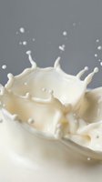 Dynamic milk splash with crown formation and droplets captured in motion against neutral background for dairy and beverage advertising campaigns.