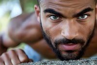Close up portrait of young African American male model with intense green eyes and well-groomed beard looking directly at camera with confident expression.