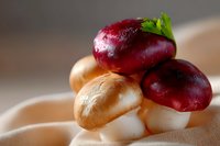 Fresh red and white mushrooms arranged on soft beige fabric with natural lighting, creating appetizing composition for food photography and culinary design.