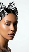Young woman with medium brown skin tone wearing polka dot bow headpiece and matching decorative ear clips, looking sideways against neutral background for fashion and beauty campaigns.