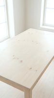 Minimalist light wood dining table with natural grain details in bright, airy room with white walls and large windows for contemporary interior design projects.