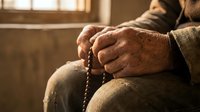 Elderly man hands holding prayer beads in contemplative moment, spiritual meditation and faith concept for religious devotion and peaceful reflection.