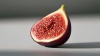 Fresh ripe fig cut in half showing juicy red flesh and seeds on light background with soft shadow, macro food photography for healthy eating concept.