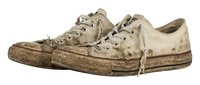 Pair of worn canvas sneakers with distressed beige fabric, dirty rubber soles, and frayed laces, suitable for grunge, vintage, or worn fashion concepts.
