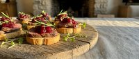 Gourmet appetizers with cranberry sauce and herbs on toasted bread served on rustic wooden board for holiday entertaining and festive dining occasions.