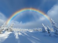 Vibrant rainbow arches over snow-covered winter forest landscape with frost-covered pine trees against bright blue sky and white fluffy clouds on sunny day.