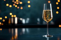 Elegant champagne flute filled with sparkling wine against blurred golden bokeh lights background for celebration and luxury dining occasions.
