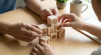 Business team building wooden blocks with icons representing teamwork, strategy and corporate development on office desk.