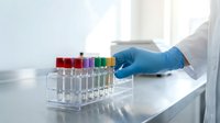 Laboratory technician in blue gloves handling colorful test tubes in a bright clinical setting. Medical research and scientific analysis concept for healthcare and diagnostics.