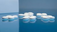 White and blue round pills scattered on a reflective blue surface, shallow depth of field, pharmaceutical concept for healthcare and medicine.