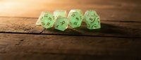 Green translucent polyhedral dice set on rustic wooden surface with warm lighting for tabletop gaming and role-playing adventures.