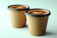Two disposable kraft paper coffee cups with fresh espresso or americano topped with crema foam on light background. Eco-friendly takeaway concept.