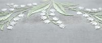 Delicate white and green floral embroidery on gray fabric with intricate stitching details for textile and craft projects.