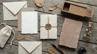 Flat lay stationery arrangement with blank cards, kraft envelopes, twine, dried leaves, and wooden accessories on rustic wood surface for branding and design projects.