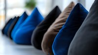 Row of colorful velvet cushions in blue, black, brown and gray tones arranged on white surface for interior design and home decor concepts.