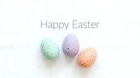 Pastel speckled Easter eggs in mint, lavender, and peach arranged on white background with Happy Easter text for greeting cards.
