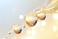 Golden water drops in macro photography with light bokeh effect creating abstract artistic composition against soft beige background. Suitable for wellness and spa designs.