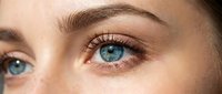 Close-up of young woman's bright blue eyes with natural makeup and well-groomed eyebrows showcasing beauty and skincare concepts for cosmetic industry.