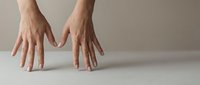 Elegant female hands with natural nude manicure resting on light surface against neutral beige background, showcasing clean minimalist beauty.