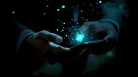Glowing turquoise particles float magically from smartphone screen in dark environment, creating ethereal atmosphere. Hands hold device displaying digital transformation concept.