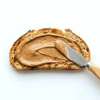 Slice of toasted bread with creamy peanut butter spread using a knife on white background, suitable for food and nutrition content.