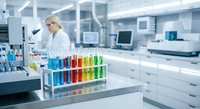 Female scientist working with colorful test tubes in modern laboratory conducting research experiments for medical analysis and chemical testing.
