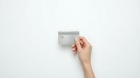 Hand holding blank gray credit card mockup against white background for financial services and banking design projects.