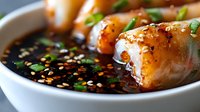 Asian dumplings in savory soy dipping sauce with sesame seeds and green onions, traditional comfort food ready for restaurant menu or cookbook photography.