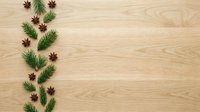 Evergreen branches and star anise arranged in vertical line on light wood surface, creating festive holiday border with copy space for seasonal designs and decorations.