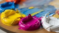 Vibrant acrylic paint colors mixed on wooden palette with brushes for artistic creativity and expression in studio workspace.