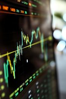 Stock market data displayed on digital screen showing green candlestick chart and financial trading information with upward trend line for investment analysis.