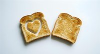 Two slices of golden toasted bread with heart-shaped cutout on white background, perfect for breakfast concepts and romantic food photography.