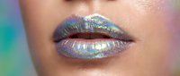 Young woman with fair complexion wearing iridescent holographic lip gloss in shimmering purple and blue tones. Close-up beauty shot showcasing cosmetic makeup application.