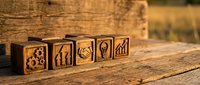Wooden blocks with business icons arranged on rustic table representing teamwork, leadership and corporate strategy concepts for presentations.
