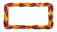 Colorful chili pepper frame border made from red, yellow and orange hot peppers isolated on white background for spicy food design and culinary projects.