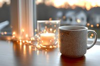 Cozy ceramic mug with hot beverage near window at sunset, fairy lights creating warm ambiance, blurred suburban houses in background, peaceful evening atmosphere.