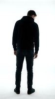 Man wearing black hoodie and dark jeans standing with back to camera against white background. Suitable for fashion, casual wear, and apparel marketing campaigns.