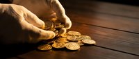 Male hand pouring golden coins onto wooden surface, symbolizing wealth, investment, financial success, and money management for business and finance concepts.