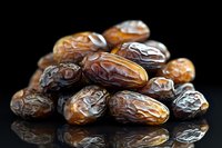Fresh Medjool dates arranged on black reflective surface with dramatic lighting, showing natural texture and rich amber colors of premium dried fruit.