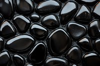 Smooth black stones with wet glossy surface create natural pattern. Dark pebbles background with light reflections shows zen and spa atmosphere.