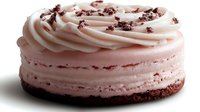 Pink strawberry cheesecake with swirled cream frosting and chocolate crumbs on white background isolated for bakery menu dessert design.