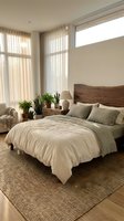 Modern minimalist bedroom with natural light streaming through large windows, wooden headboard, neutral bedding, and green plants creating serene atmosphere.